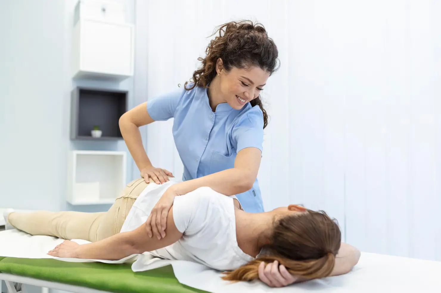young woman chiropractor fixing womans back with hands movements